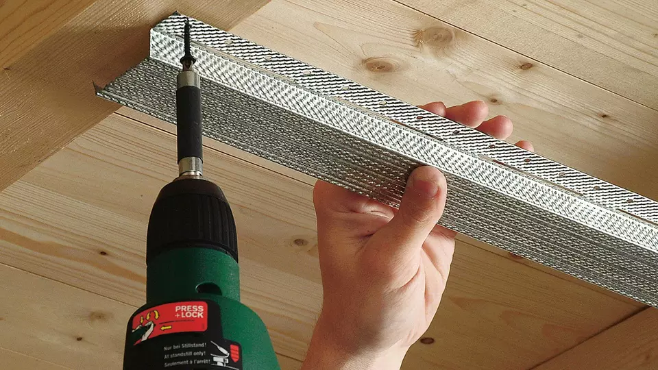 Vastschroeven van een metalen rachel op houten balken voor een verlaagd plafond